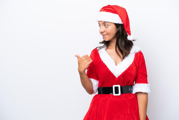 Young hispanic woman dressed as mama noel isolated on white background pointing to the side to present a product