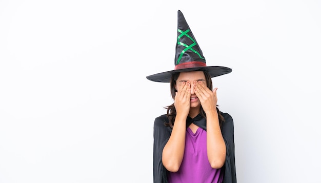 Young hispanic woman dressed as witch over isolated background covering eyes by hands and smiling