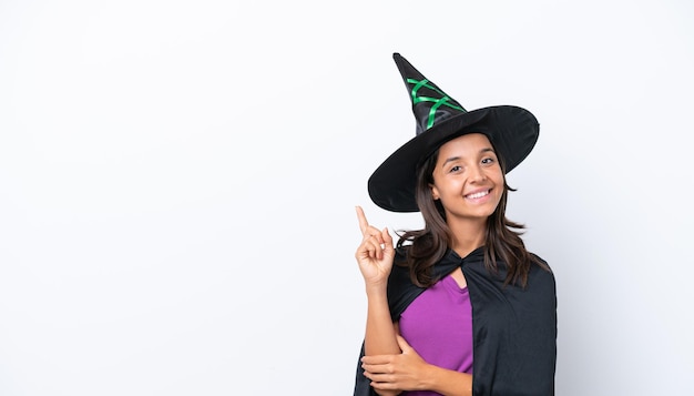 Young hispanic woman dressed as witch over isolated background happy and pointing up