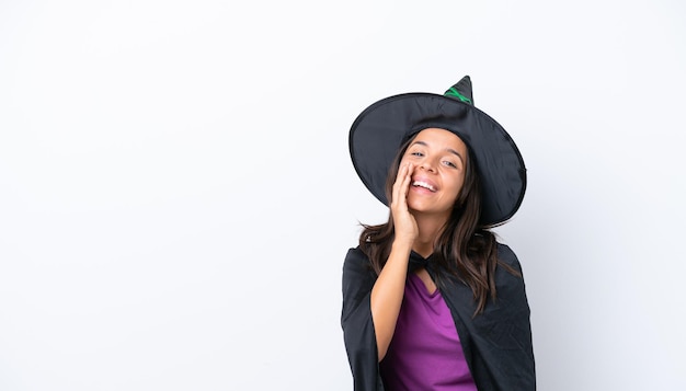 Young hispanic woman dressed as witch over isolated background shouting with mouth wide open