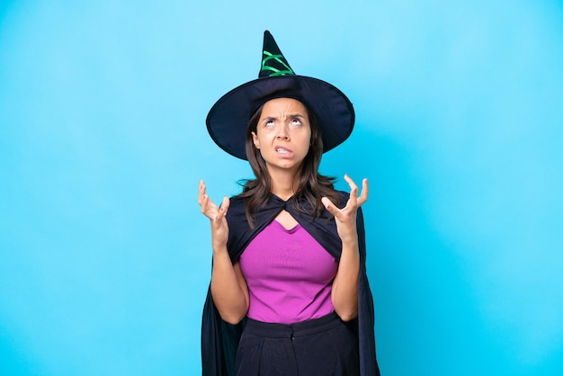 Young hispanic woman dressed as witch over isolated background stressed overwhelmed