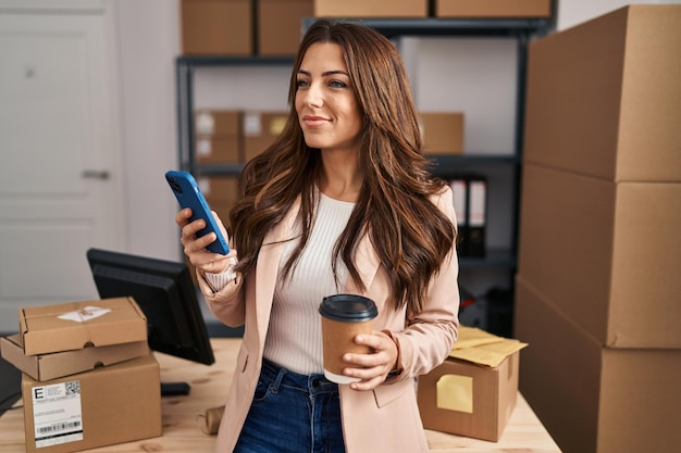 Young hispanic woman ecommerce business worker using smartphone at office