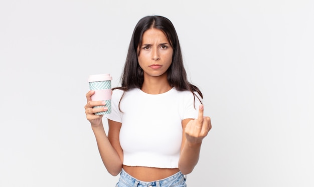 Young hispanic woman feeling angry, annoyed, rebellious and aggressive and holding a take away coffee container