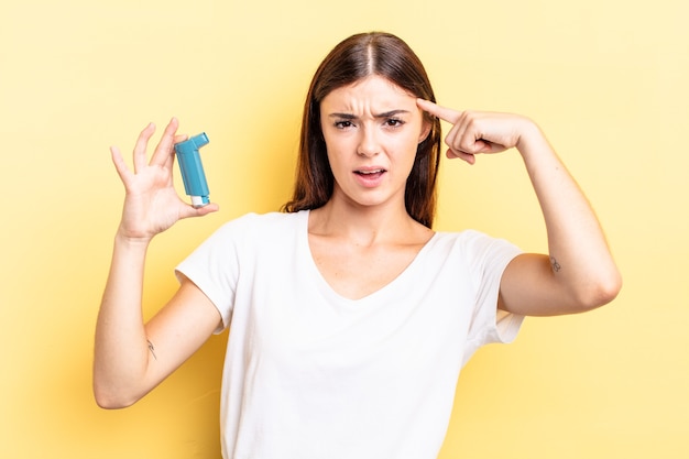 Young hispanic woman feeling confused and puzzled, showing you are insane. asthma concept