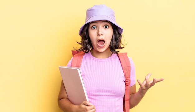 Young hispanic woman feeling extremely shocked and surprised. back to school concept