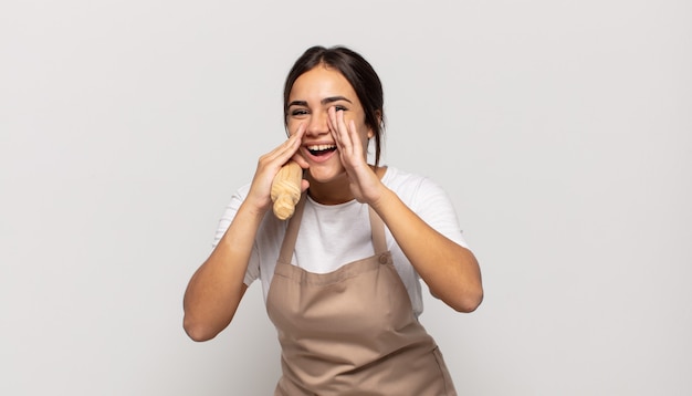 young hispanic woman feeling happy, excited and positive, giving a big shout out with hands next to mouth, calling out