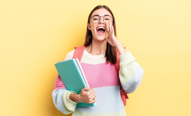 Young hispanic woman feeling happy,giving a big shout out with hands next to mouth. student concept