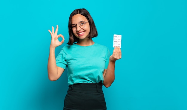 Young hispanic woman feeling happy, relaxed and satisfied, showing approval with okay gesture, smiling