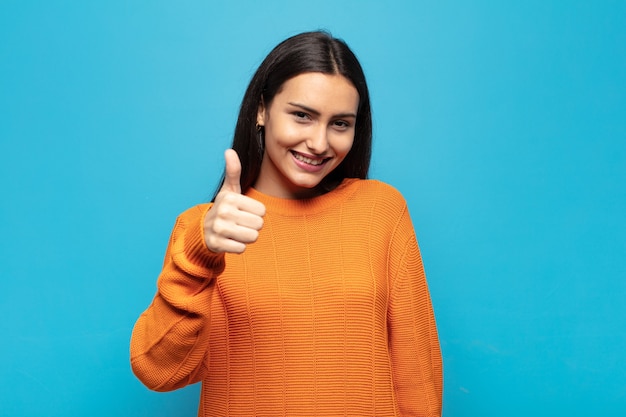 Young hispanic woman feeling proud, carefree, confident and happy, smiling positively with thumbs up