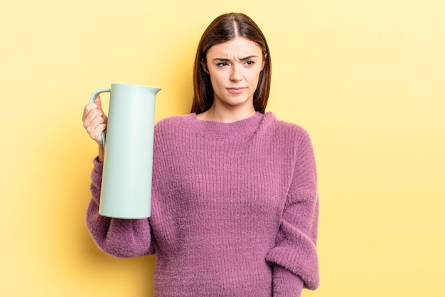 Young hispanic woman feeling sad, upset or angry and looking to the side. coffee thermos concept