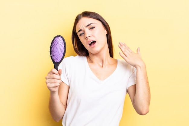 Young hispanic woman feeling stressed, anxious, tired and frustrated. hair brush concept