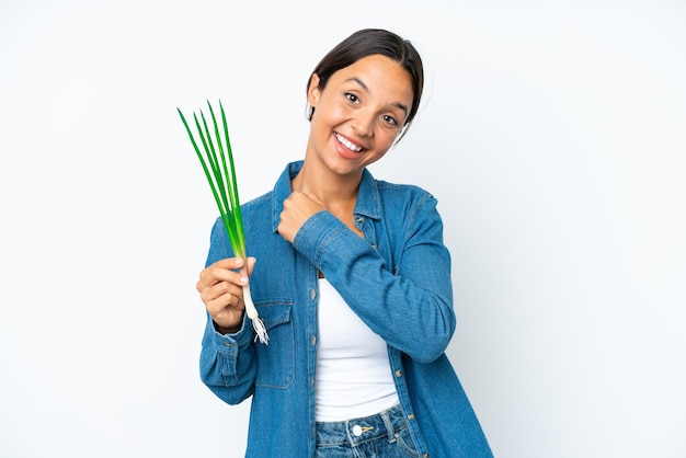 Young hispanic woman holding chive isolated on white background celebrating a victory