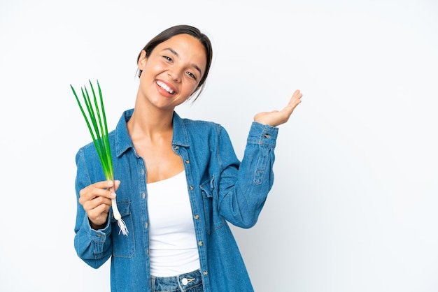 Young hispanic woman holding chive isolated on white background extending hands to the side for inviting to come