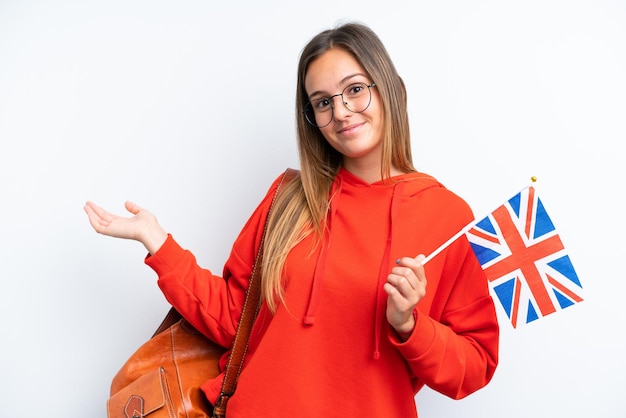 Young hispanic woman holding an United Kingdom flag isolated on white background extending hands to the side for inviting to come