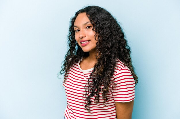 Young hispanic woman isolated on blue background confident keeping hands on hips