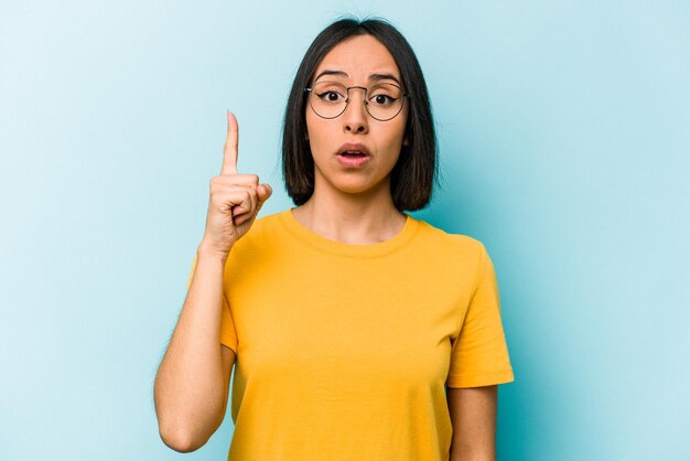 Young hispanic woman isolated on blue background having an idea inspiration concept