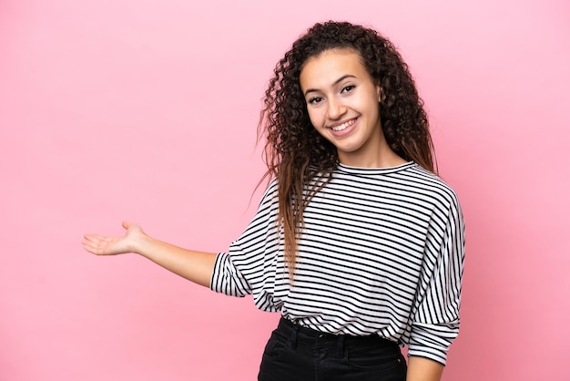 Young hispanic woman isolated on pink background extending hands to the side for inviting to come