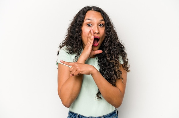 Young hispanic woman isolated on white background saying a gossip pointing to side reporting something