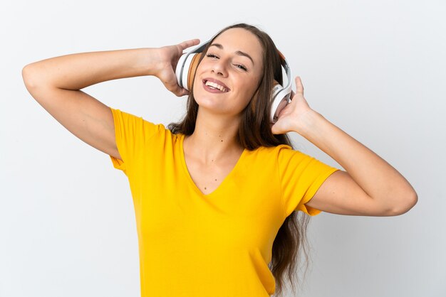 Young hispanic woman over isolated white wall listening music