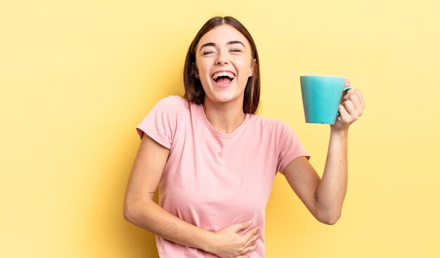 Young hispanic woman laughing out loud at some hilarious joke. coffee cup concept