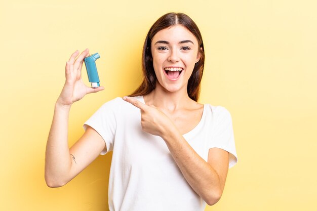 Young hispanic woman looking excited and surprised pointing to the side. asthma concept