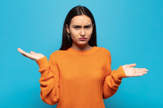 Young hispanic woman looking puzzled, confused and stressed, wondering between different options, feeling uncertain