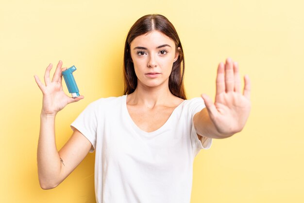 Young hispanic woman looking serious showing open palm making stop gesture. asthma concept