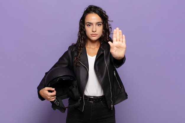 Young hispanic woman looking serious, stern, displeased and angry showing open palm making stop gesture