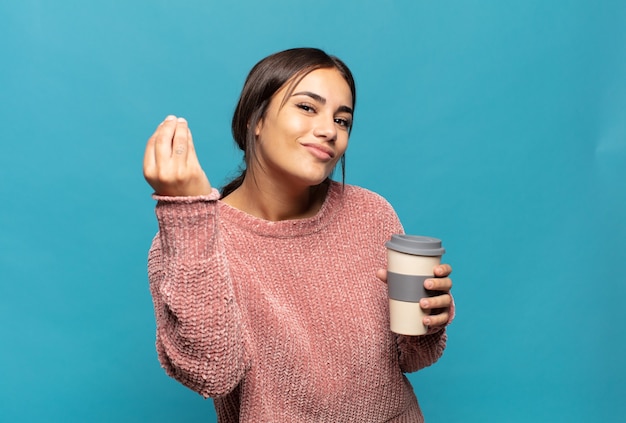 Young hispanic woman making capice or money gesture, telling you to pay your debts!