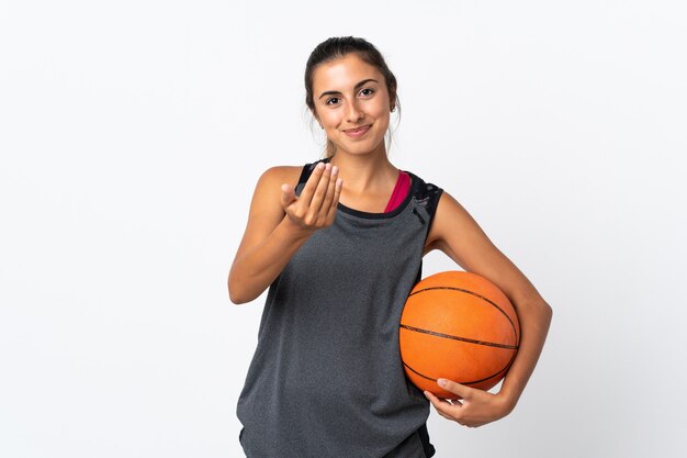 Young hispanic woman playing basketball over isolated white wall inviting to come with hand. Happy that you came