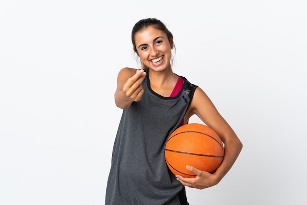 Young hispanic woman playing basketball over isolated white wall making money gesture