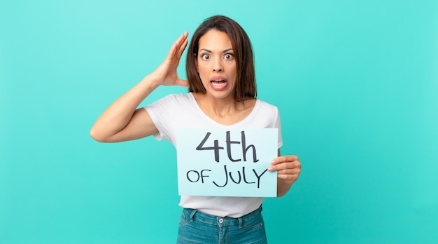 Young hispanic woman screaming with hands up in the air independence day concept