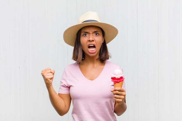 Young hispanic woman shouting aggressively with an angry expression or with fists clenched celebrating success