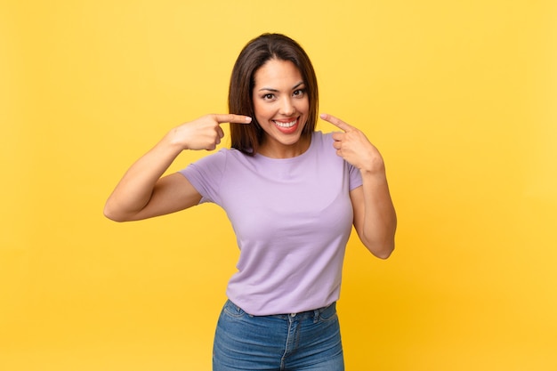 Young hispanic woman smiling confidently pointing to own broad smile