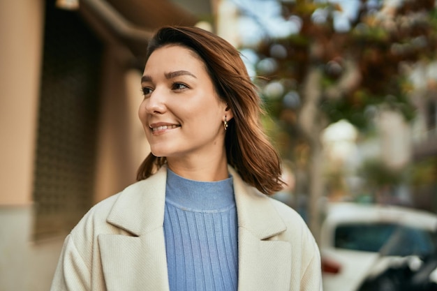 Young hispanic woman smiling happy standing at the city