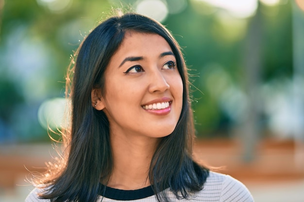 Young hispanic woman smiling happy walking at the park