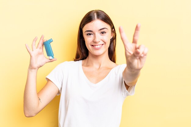 Young hispanic woman smiling and looking friendly, showing number two. asthma concept