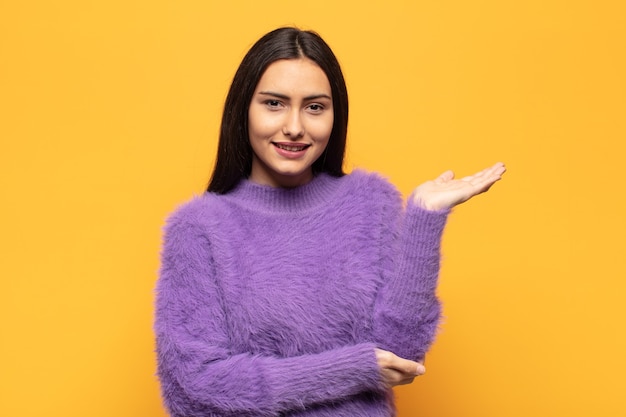 Young hispanic woman smiling proudly and confidently, feeling happy and satisfied and showing a concept on copy space