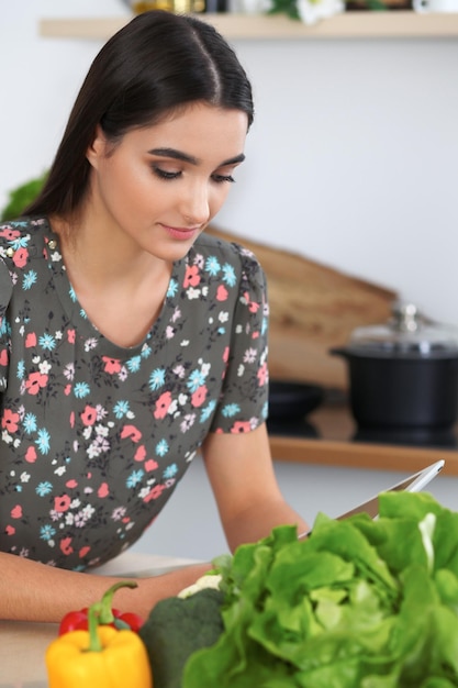 Young hispanic woman or student cooking in kitchen Girl using tablet to make online shopping or find a new recipe