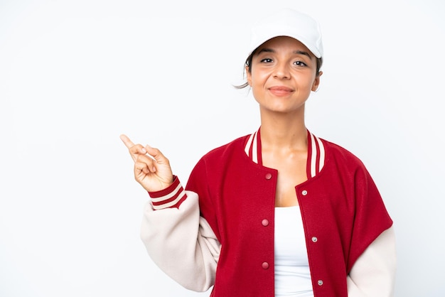 Young hispanic woman wearing a baseball uniform isolated on white background pointing to the side to present a product