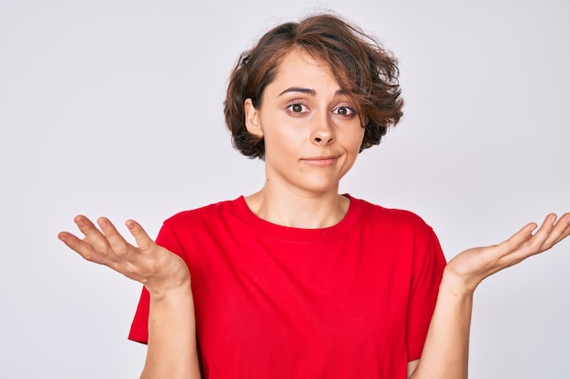 Young hispanic woman wearing casual clothes clueless and confused with open arms, no idea and doubtful face.