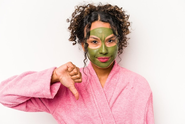 Young hispanic woman wearing a facial mask isolated on white background showing a dislike gesture thumbs down Disagreement concept