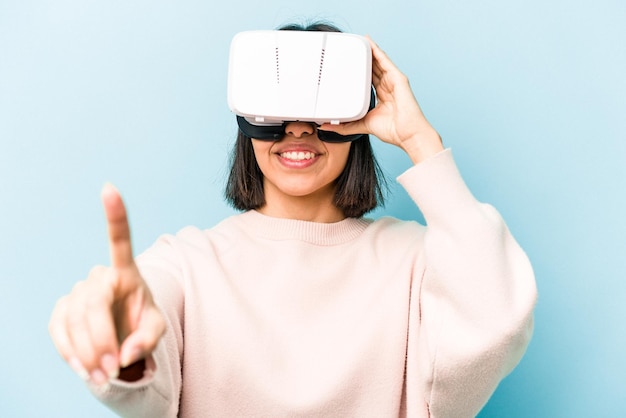 Young hispanic woman wearing a virtual glasses isolated on blue background