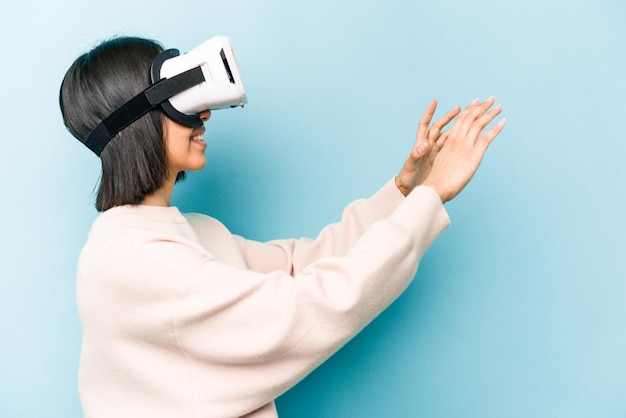 Young hispanic woman wearing a virtual glasses isolated on blue background