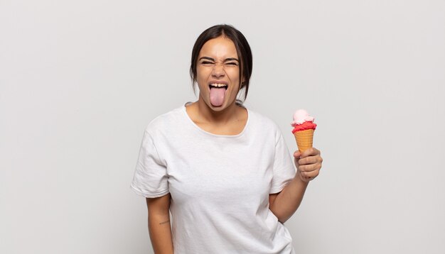 Young hispanic woman with cheerful, carefree, rebellious attitude, joking and sticking tongue out, having fun