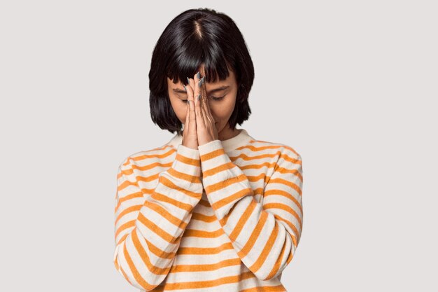 Young Hispanic woman with short black hair in studio holding hands in pray near