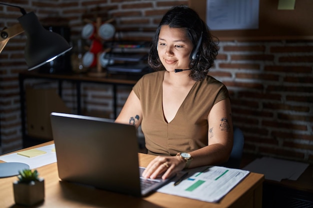 Young hispanic woman working at the office at night relaxed with serious expression on face simple and natural looking at the camera