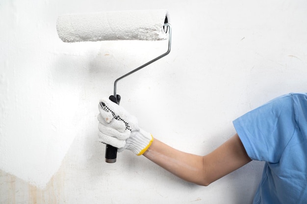 Young housewife hands in glove holding paint roller brush