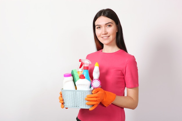 A young housewife holds in his hands cleaning products on a colored background