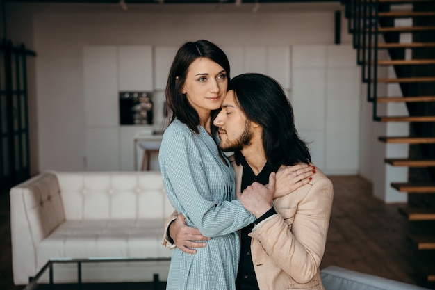 Young husband gently hugs his wife in the living room. High quality photo